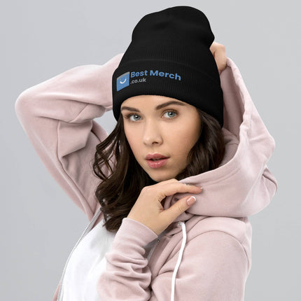 Black Cuffed Best Merch Beanie featuring blue logo, modeled by woman in pink hoodie. Cozy and trendy branded headwear.