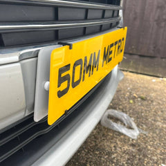 Show Plate Holder Clips securely mounting a yellow number plate on a vehicle front bumper; pack of 4 clips, plate not included.